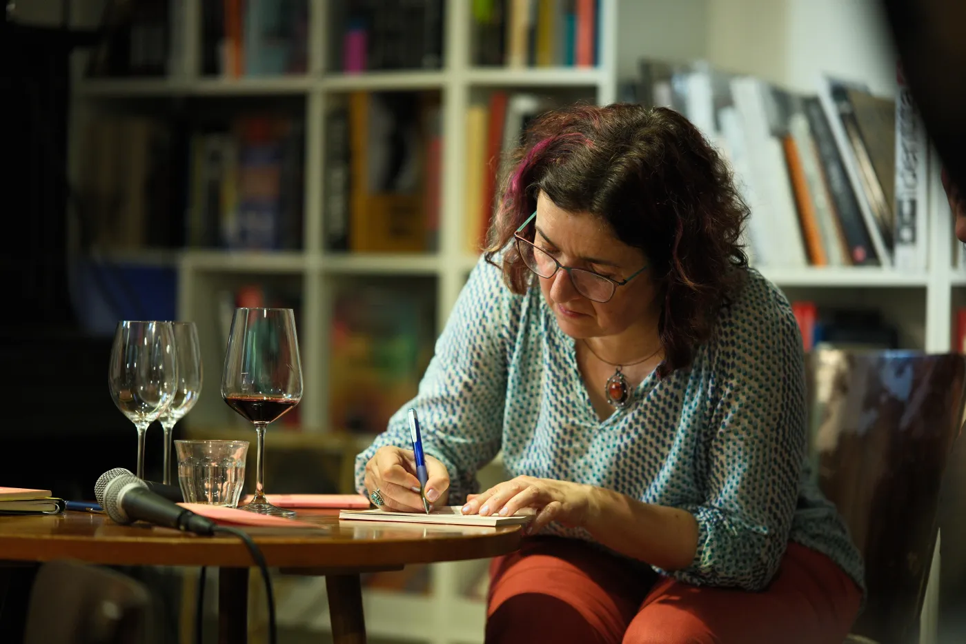 Lenka Kapsová podepisuje knihu Meandry u stolku s mikrofonem